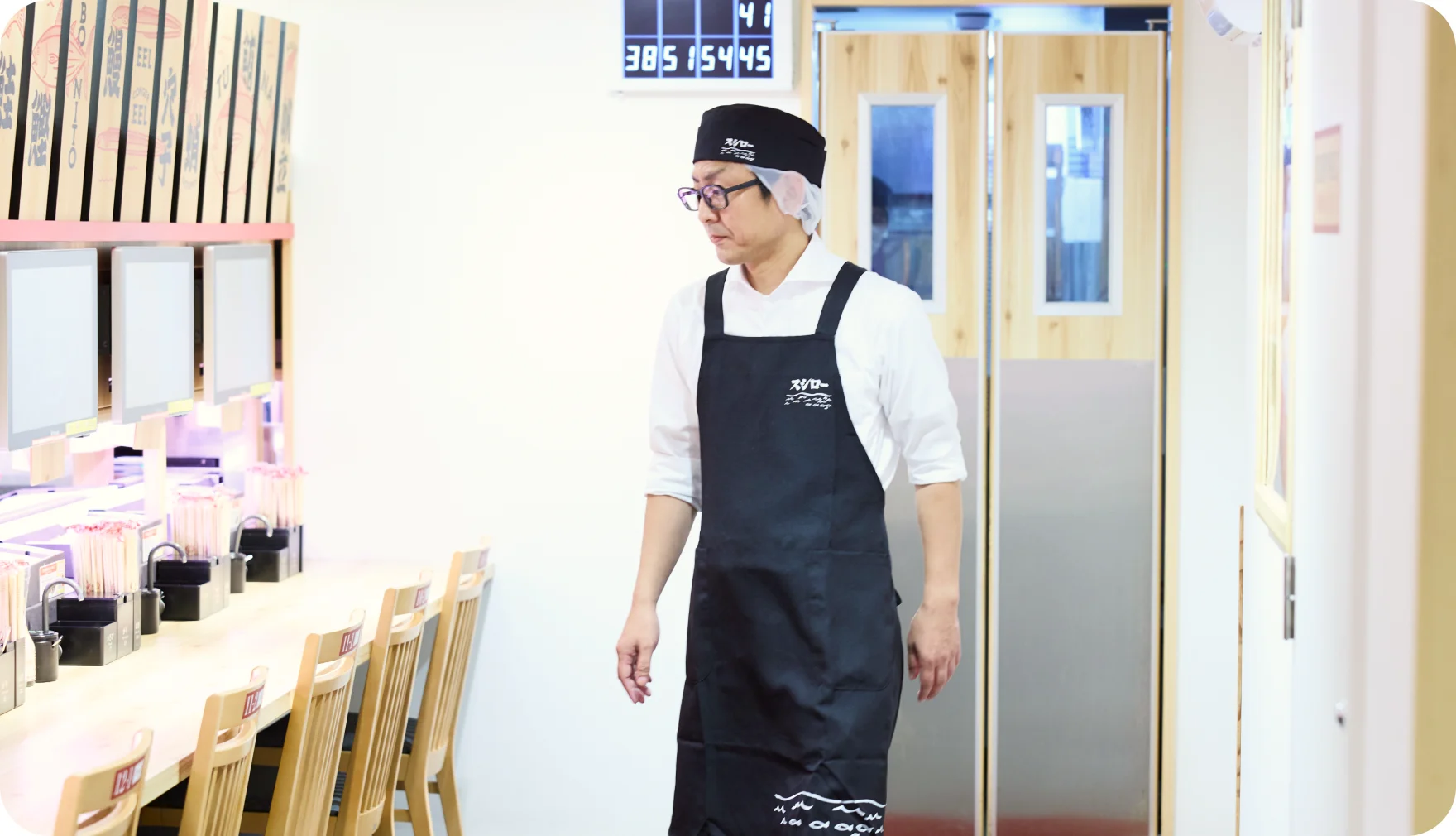 レーン脇の通路で店内を見回る花輪博行